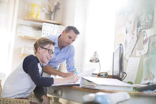 Pai ajudando filho adolescente fazendo seu dever de casa no quarto — Fotografia de Stock