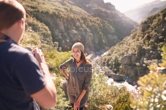 Young man photographing girlfriend at sunny overlook — Stock Photo