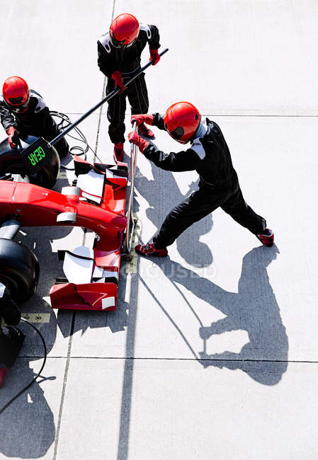 Overhead pit crew with hydraulic lift in pit lane — Stock Photo