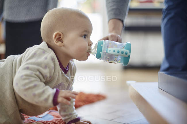 Baby girl crawling and drinking from sip cup — Stock Photo