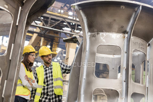 Trabajadores siderúrgicos examinando parte en fábrica - foto de stock