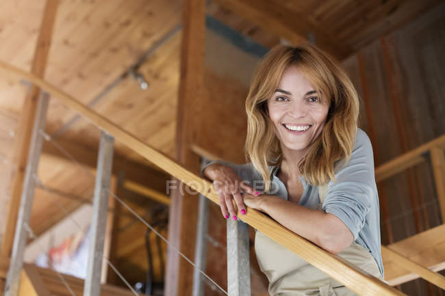 Portrait smiling artist on staircase in modern art studio — Stock Photo