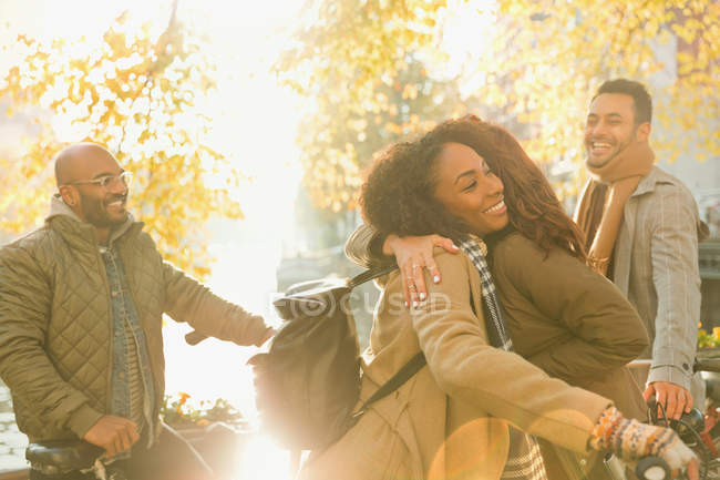 Freunde mit Fahrrädern grüßen und umarmen sich auf der sonnigen Herbststraße — Stockfoto