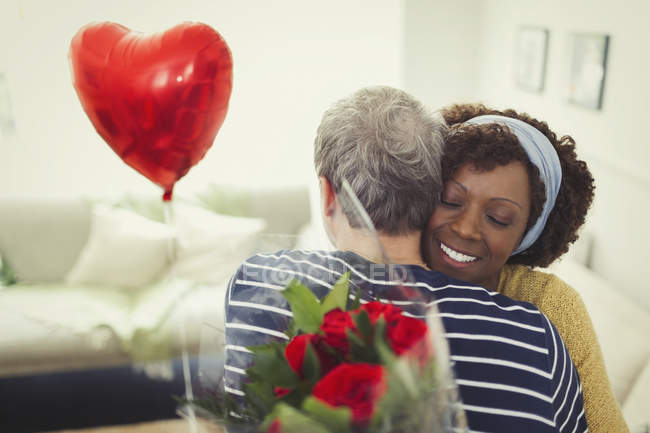 Frau umarmt Ehemann gibt Valentinstag Ballon und Rosenstrauß — Stockfoto