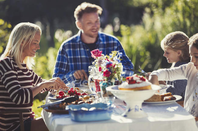 Família comendo no jardim ensolarado festa mesa de pátio — Fotografia de Stock
