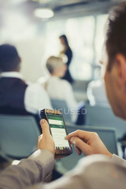 Businessman texting with cell phone in conference audience — Stock Photo