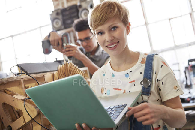 Портрет усміхненої жінки-дизайнера, що використовує ноутбук у майстерні — стокове фото