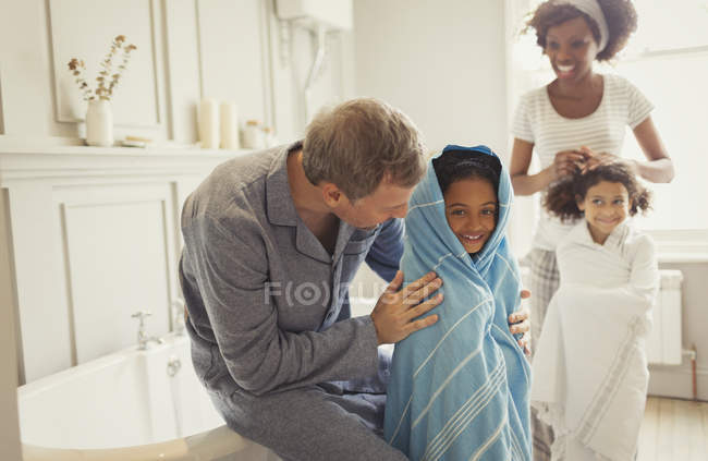 Multi-ethnic parents drying daughters with towels after bath time in bathroom — Stock Photo