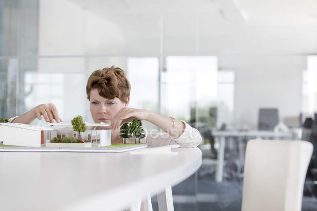 Focused female architect arranging model in conference room — Stock Photo