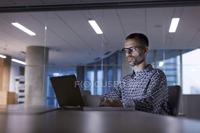 Empresário trabalhando até tarde no laptop no escritório — Fotografia de Stock