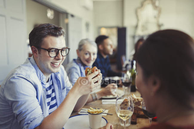 Friends talking and eating at restaurant table — Stock Photo