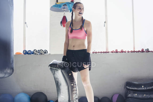 Confident young female boxer with padding in gym — Stock Photo