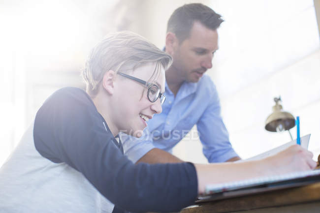 Отец помогает сыну-подростку с домашним заданием — стоковое фото