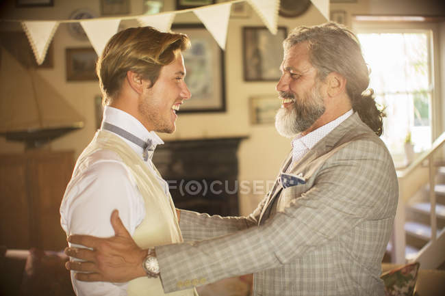 Best man and bridegroom standing and laughing in domestic room — Stock Photo