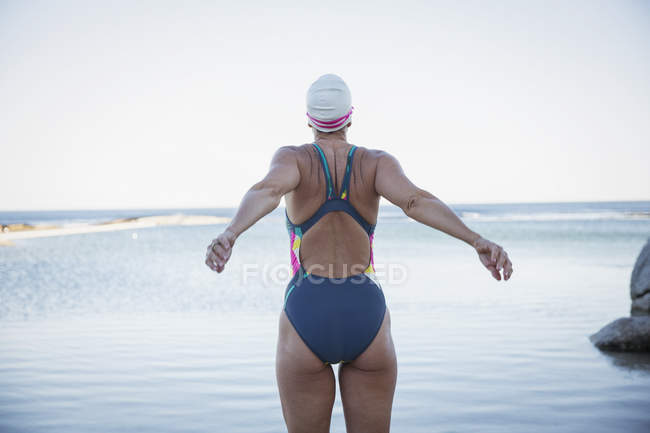 Femme nageuse souriante s'étirant à l'océan à l'extérieur — Photo de stock