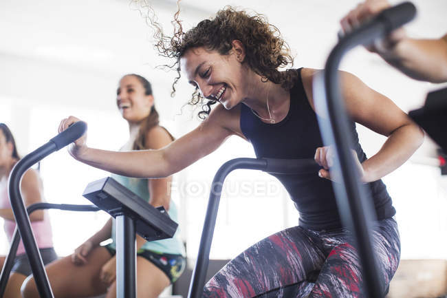 Smiling, playful young woman using elliptical bike in gym — Stock Photo
