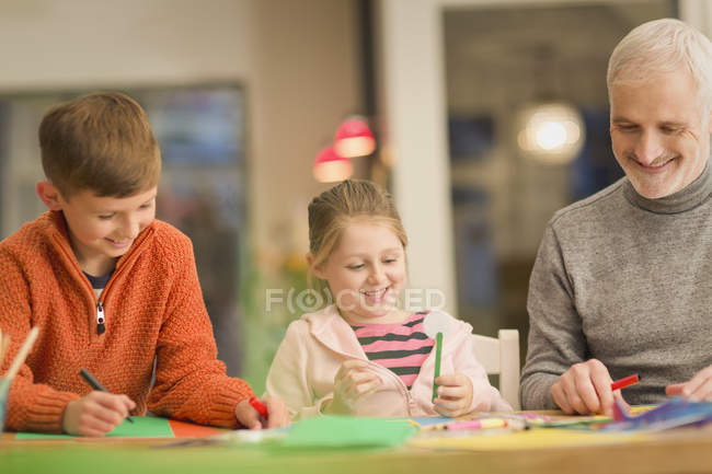 Padre e hijos vinculándose, haciendo manualidades en la mesa - foto de stock