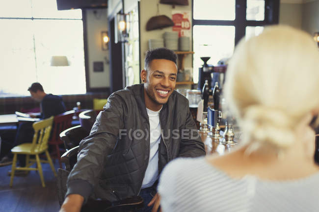 Lächelnder Mann im Gespräch mit Frau in Bar — Stockfoto