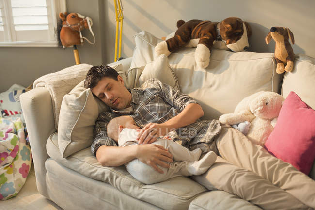 Exausto pai e bebê filho dormindo no sofá — Fotografia de Stock