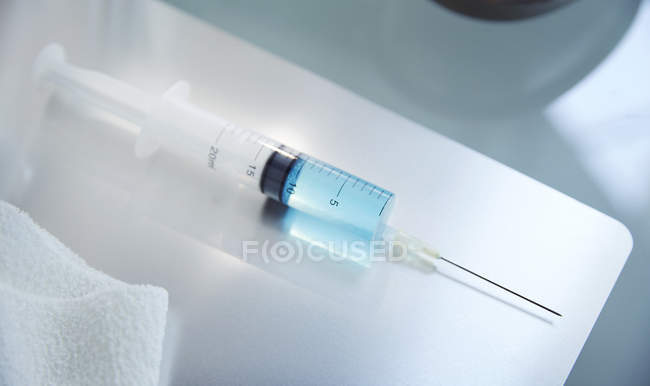 Vue de la seringue avec fluide bleu sur la table en laboratoire — Photo de stock