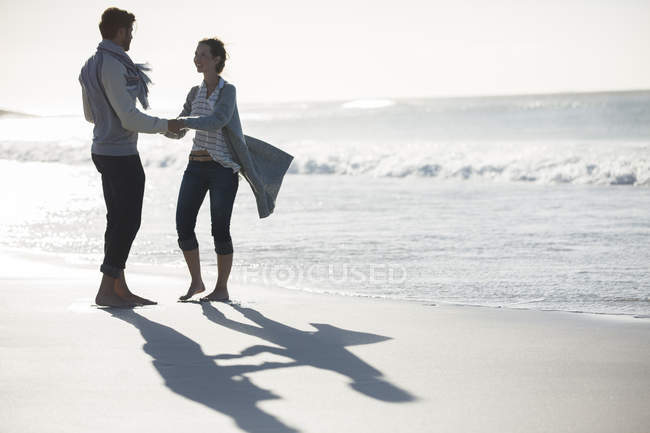 Giovane coppia che si tiene per mano sulla spiaggia — Foto stock