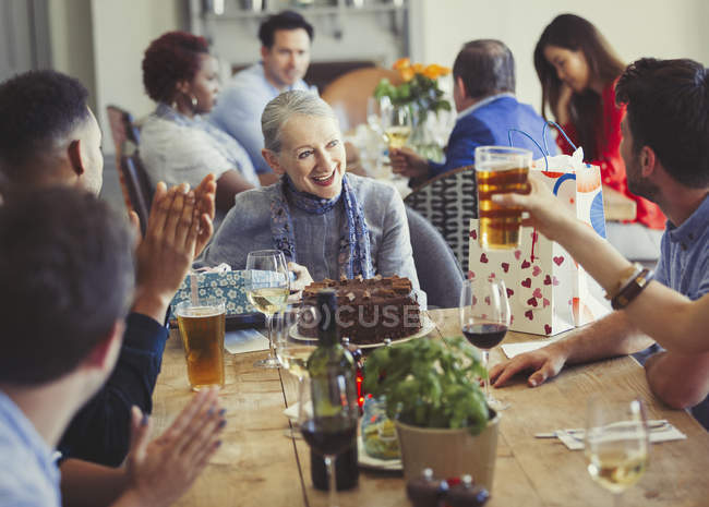 Женщина наслаждается днем рождения с друзьями за столом ресторана — стоковое фото