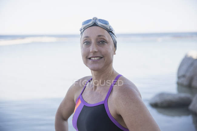 Sonriente nadadora femenina caminando en el océano al aire libre - foto de stock