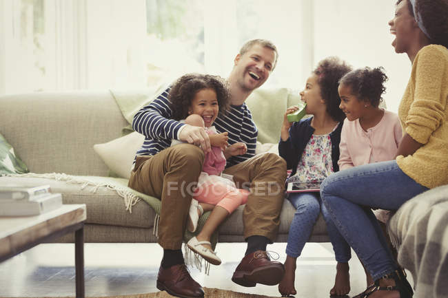 Familia joven multiétnica riendo en el sofá - foto de stock