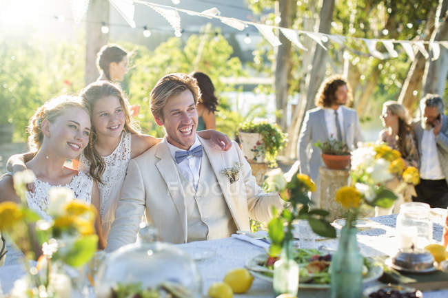 Jeune couple et demoiselle d'honneur lors de la réception de mariage dans le jardin domestique — Photo de stock