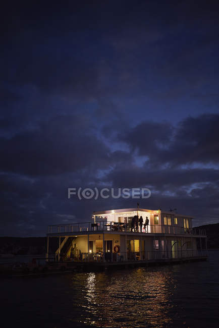 Casa flotante de verano iluminado en el océano noche - foto de stock