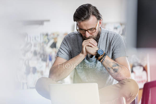 Diseño masculino pensativo profesional que trabaja en el ordenador portátil - foto de stock