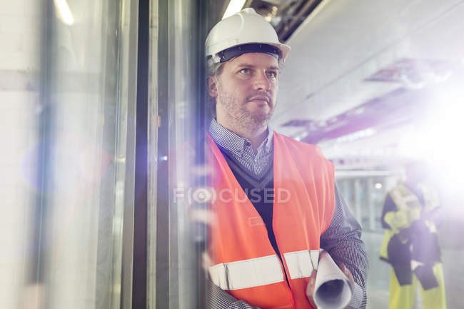 Серйозний чоловічий інженер з кресленнями на будівельному майданчику — стокове фото