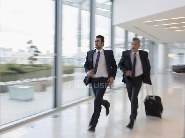 Des hommes d'affaires courent, se précipitent avec une valise à l'aéroport — Photo de stock