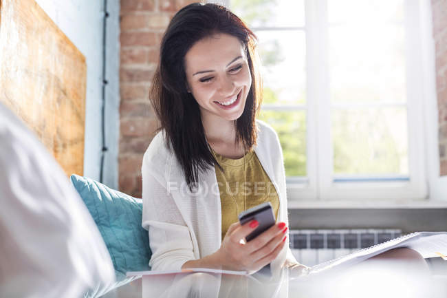 Улыбающаяся женщина пишет смс с сотовым на кровати — стоковое фото