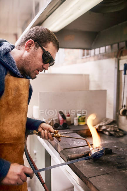Ювелирный нагреватель металла с помощью факела в мастерской — стоковое фото