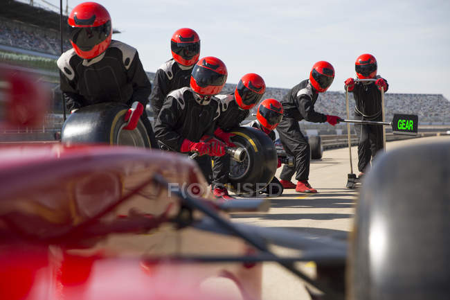 Pit crew with tires ready for nearing formula one race car in pit lane — Stock Photo