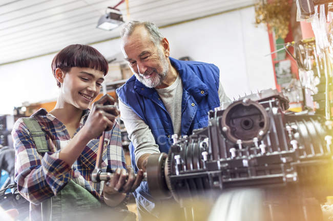 Male and female motorcycle mechanics repairing engine in workshop — Stock Photo