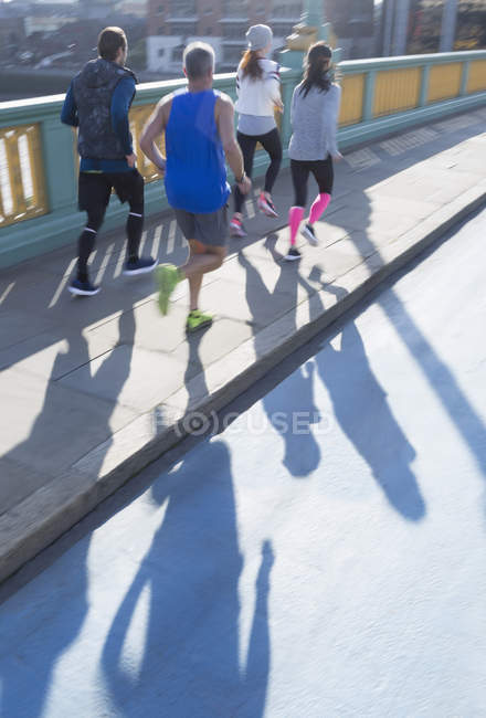 Läufer laufen auf sonnigem städtischen Brückensteg — Stockfoto