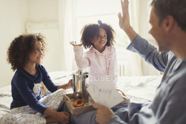 Père recevant la carte de la fête des pères de filles et de haute-cinq sur le lit — Photo de stock