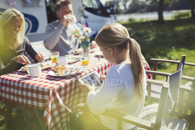 Девушка с цифровым планшетом за завтраком возле солнечного дома на колесах — стоковое фото