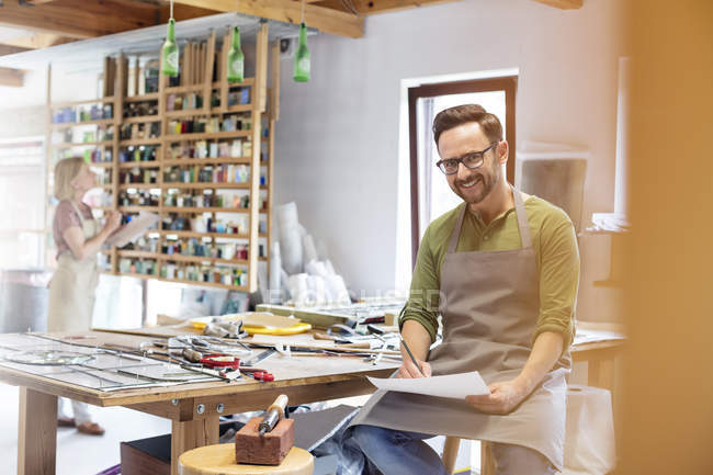 Portrait smiling stained glass artist working in studio — Stock Photo