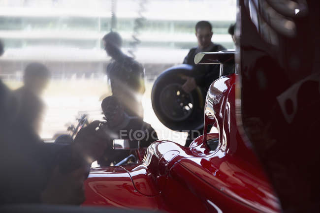 Equipaggio pozzo di lavoro sulla formula uno auto da corsa in garage di riparazione — Foto stock