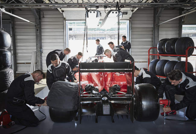 Pit équipe de travail sur la formule une voiture de course dans le garage de réparation — Photo de stock