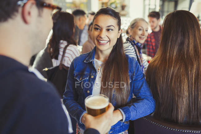 Man and woman drinking beer and talking at bar — Stock Photo