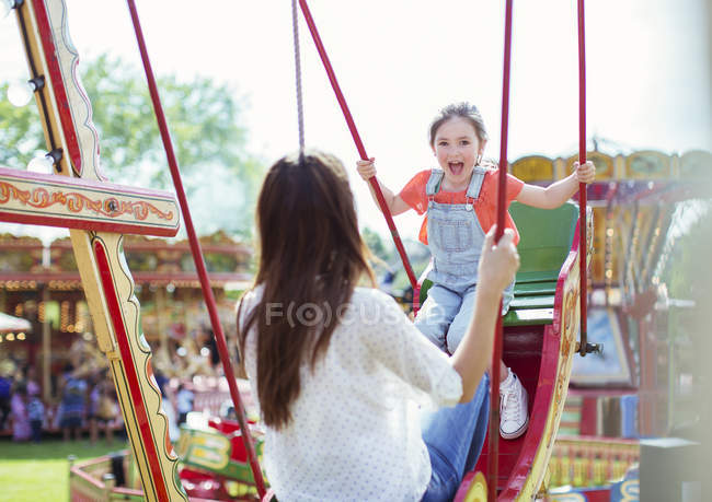 Mère et fille jouant sur swing dans le parc d'attractions — Photo de stock