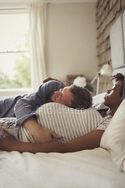 Affectionate pregnant couple cuddling and napping on bed — Stock Photo