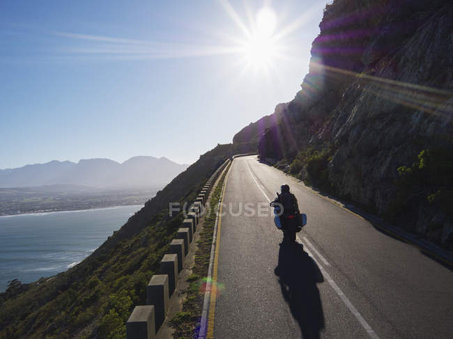 Paar fährt Motorrad auf sonniger Straße am Meer entlang — Stockfoto