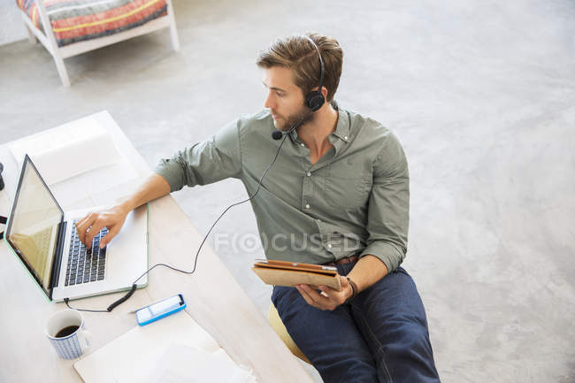 Молодий чоловік сидить за столом, працює з ноутбуком — стокове фото