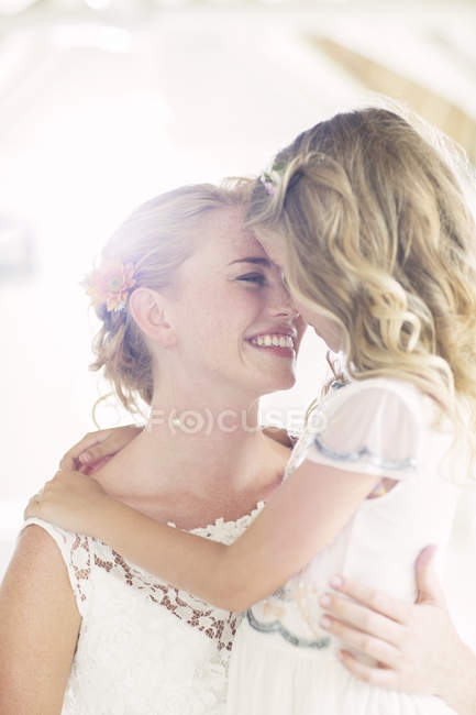 Bride holding bridesmaid in domestic room — Stock Photo