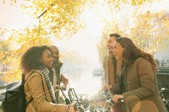 Young friends with bicycles along sunny autumn canal — Stock Photo